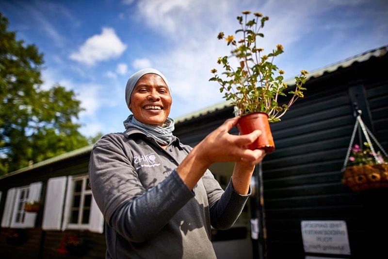 Ozichi Brewster, Therapeutic Gardener, holds a plant for the Wellbeing Garden